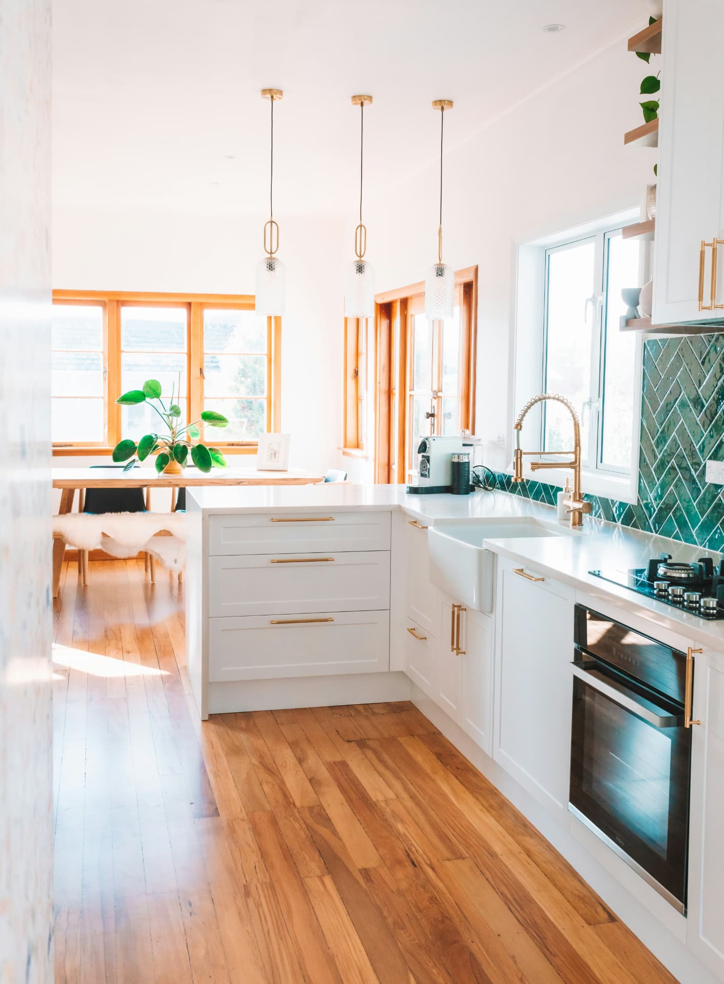 White kitchen with natural wood floorboards and gold fixtures