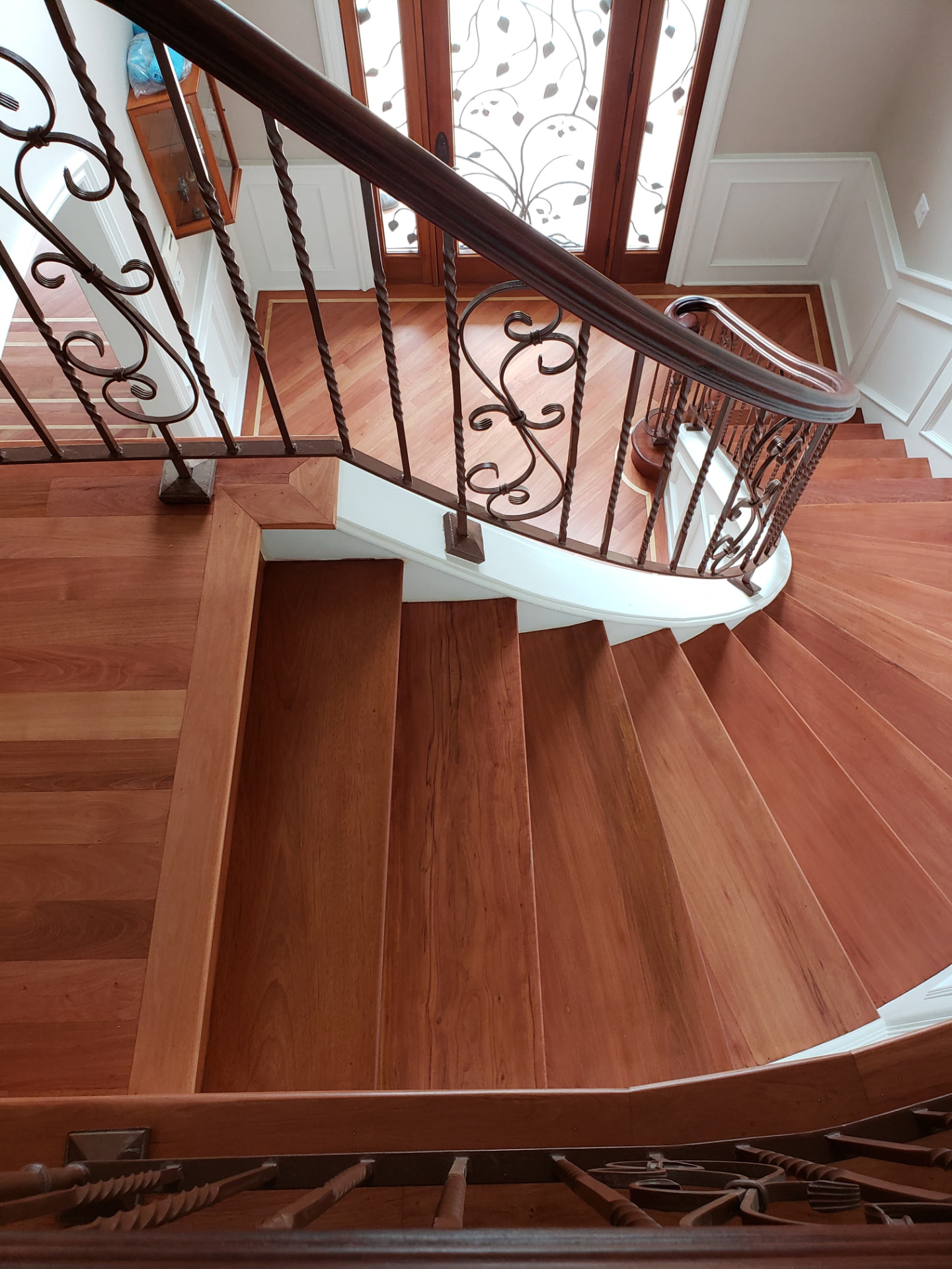 Curved staircase with rich cherry hardwood and wrought-iron railings